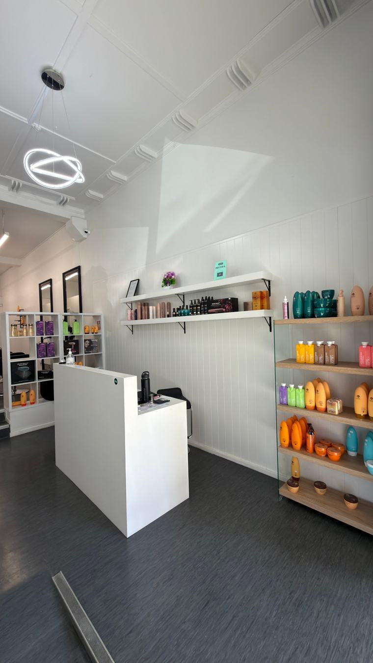 Reception area at Nova Hair & Beauty with product shelves and a ring pendant light