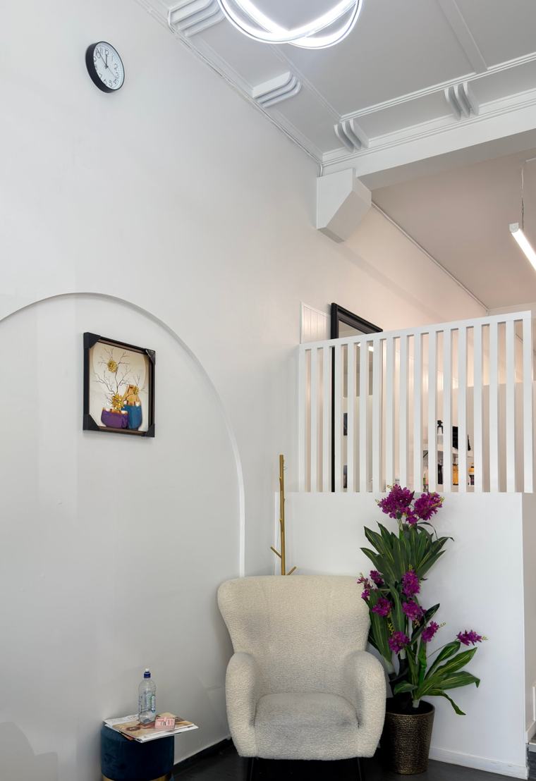 Waiting area at Nova Hair & Beauty with a cream armchair, orchids and an arched feature wall